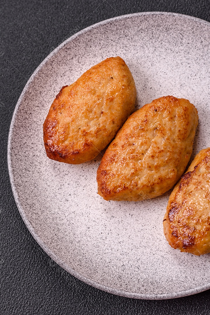 Deliciosas costeletas de peixe picado frito fresco com especiarias e ervas sobre um fundo escuro de concreto