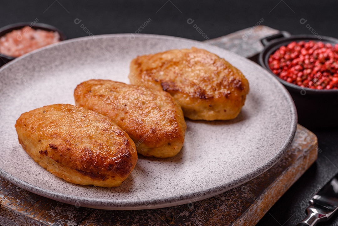 Deliciosas costeletas de peixe picado frito fresco com especiarias e ervas sobre um fundo escuro de concreto