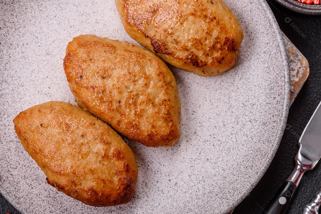 Deliciosas costeletas de peixe picado frito fresco com especiarias e ervas sobre um fundo escuro de concreto