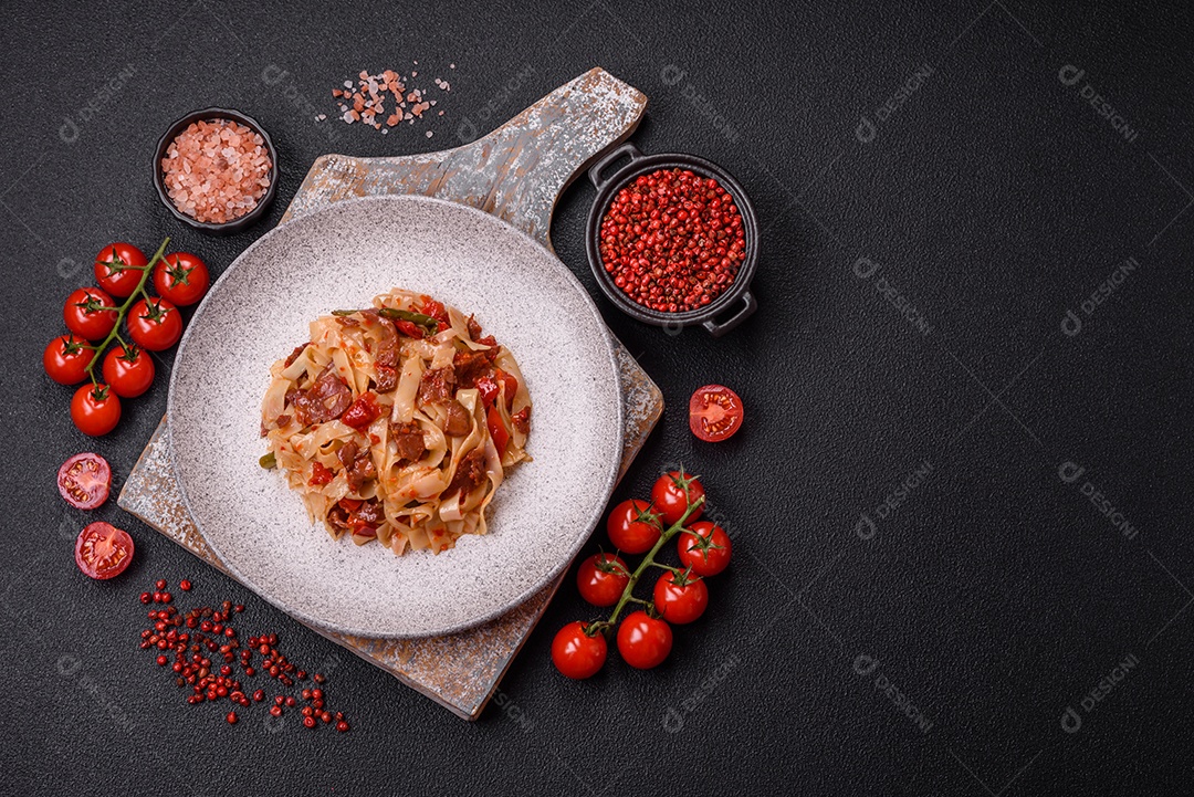 Delicioso prato de udon asiático com legumes, carne, sal e especiarias numa placa cerâmica sobre um fundo escuro de concreto