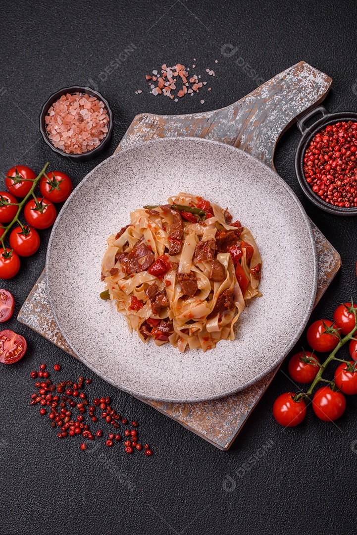 Delicioso prato de udon asiático com legumes, carne, sal e especiarias numa placa cerâmica sobre um fundo escuro de concreto