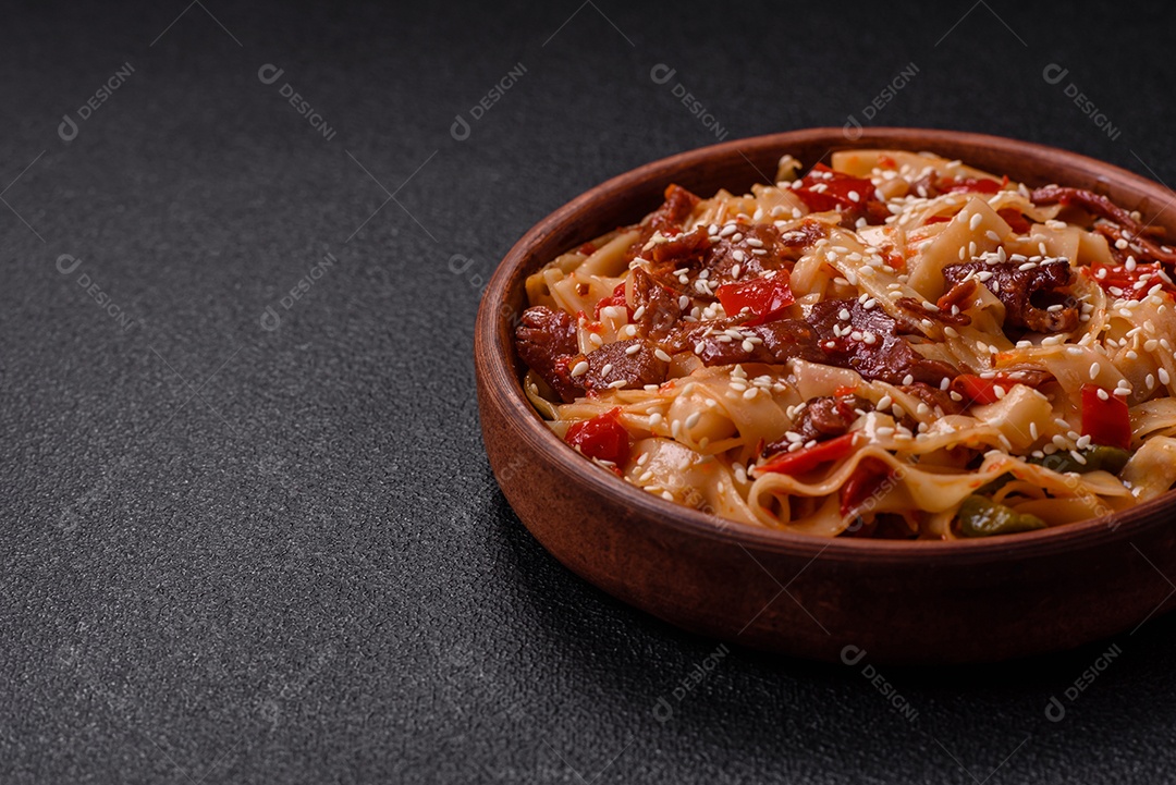 Delicioso prato de udon asiático com legumes, carne, sal e especiarias numa placa cerâmica sobre um fundo escuro de concreto