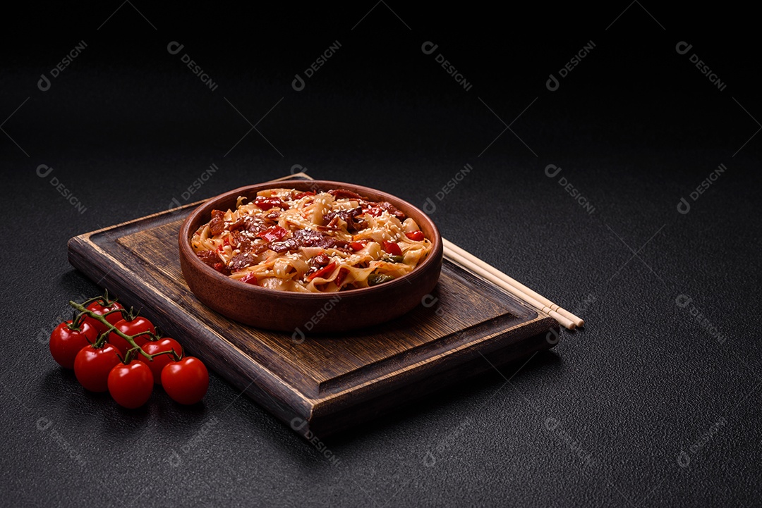 Delicioso prato de udon asiático com legumes, carne, sal e especiarias numa placa cerâmica sobre um fundo escuro de concreto