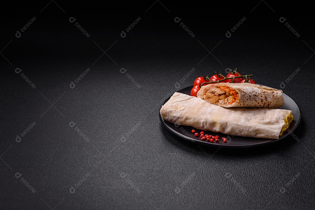 Delicioso rolo suculento ou shawarma com frango, tomate, salada e molho sobre um fundo escuro de concreto