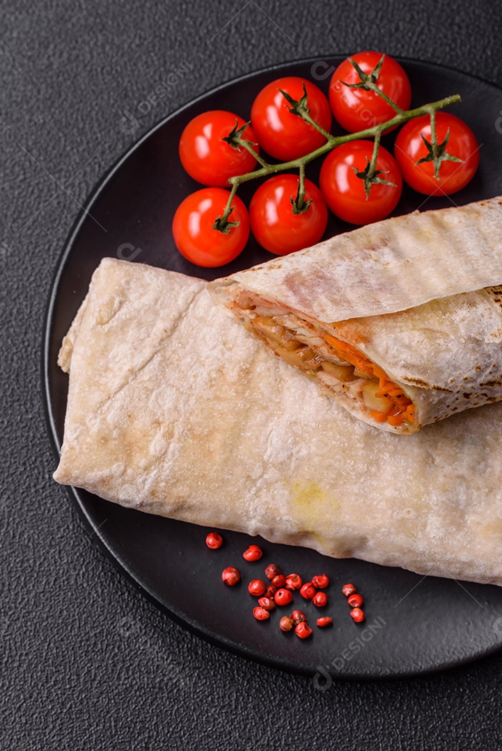 Delicioso rolo suculento ou shawarma com frango, tomate, salada e molho sobre um fundo escuro de concret