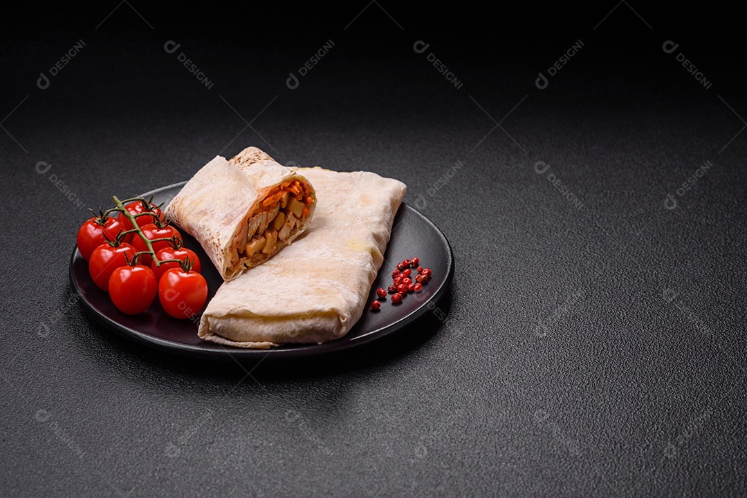 Delicioso rolo suculento ou shawarma com frango, tomate, salada e molho sobre um fundo escuro de concreto