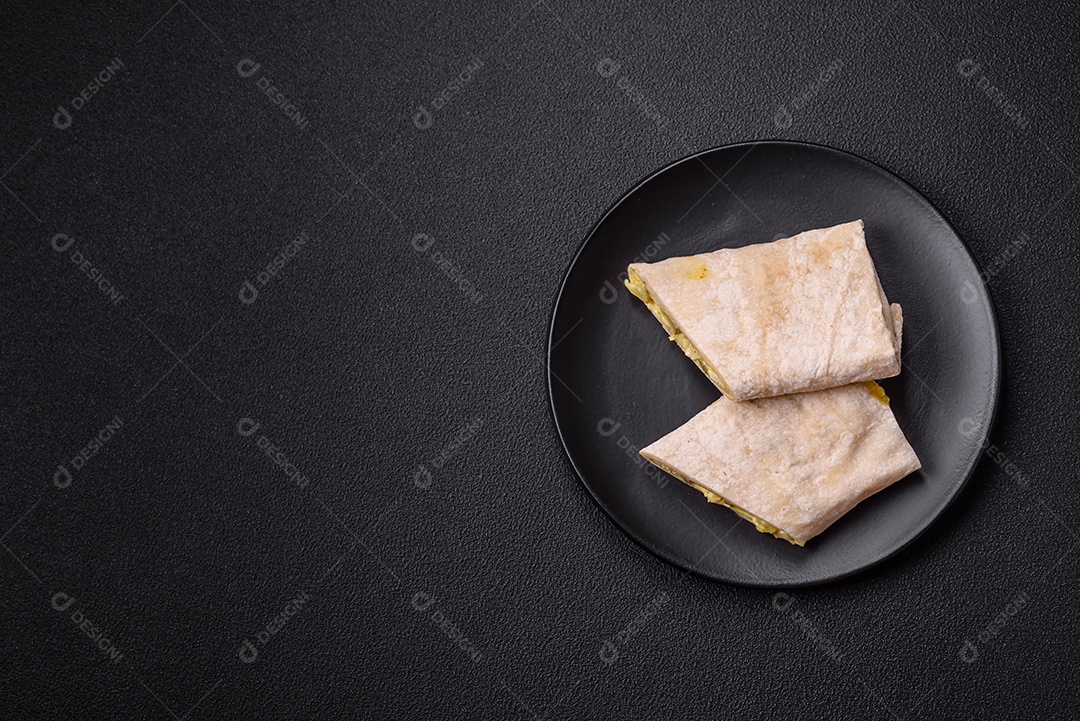 Delicioso rolo suculento ou shawarma com frango, tomate, salada e molho sobre um fundo escuro de concreto