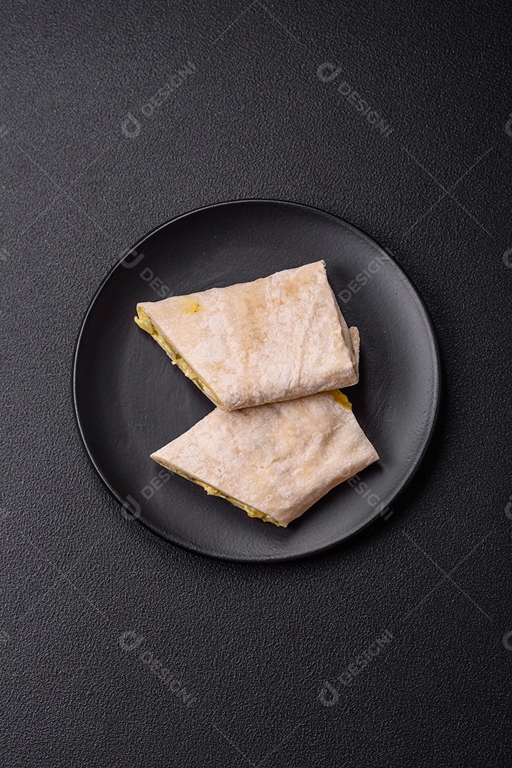 Delicioso rolo suculento ou shawarma com frango, tomate, salada e molho sobre um fundo escuro de concreto