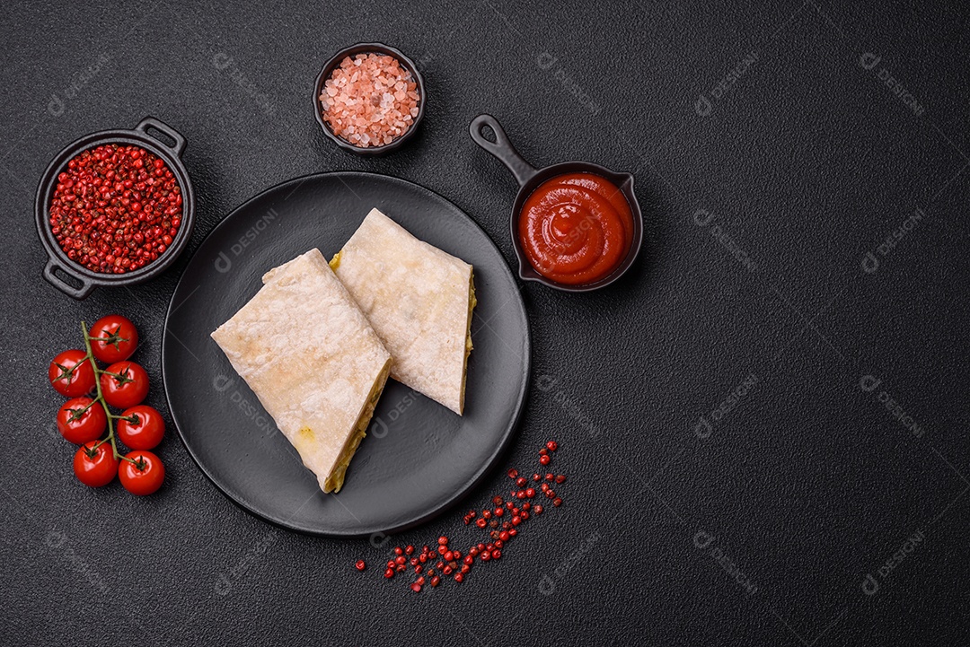 Delicioso rolo suculento ou shawarma com frango, tomate, salada e molho sobre um fundo escuro de concreto