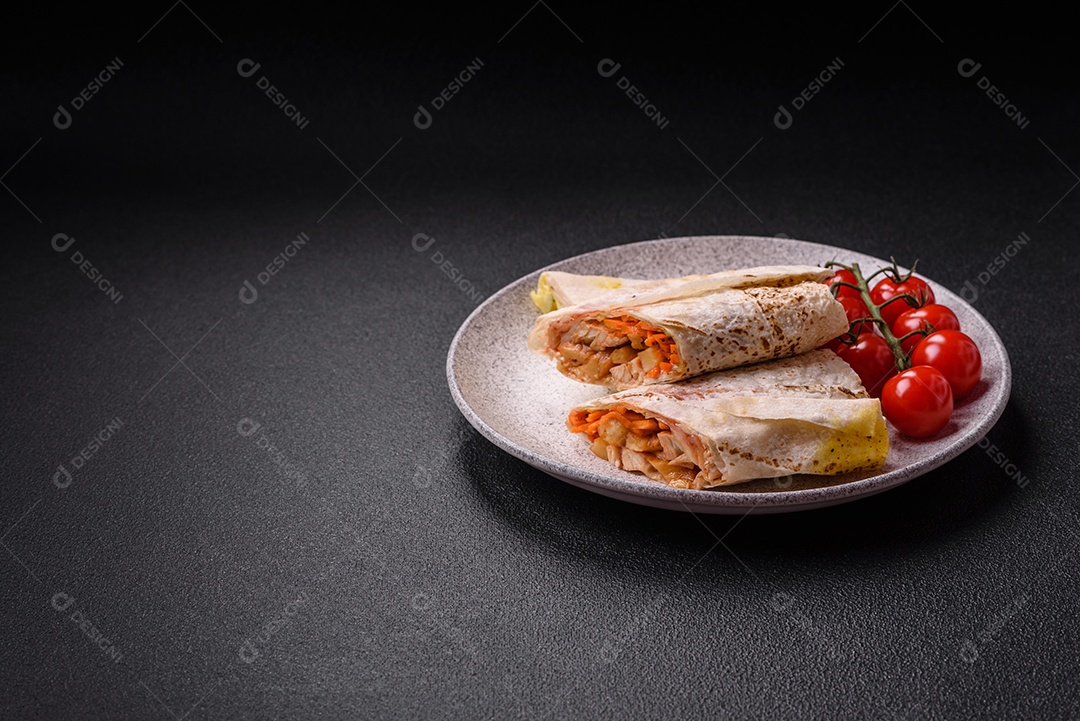 Delicioso rolo suculento ou shawarma com frango, tomate, salada e molho sobre um fundo escuro de concreto