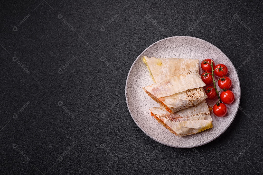 Delicioso rolo suculento ou shawarma com frango, tomate, salada e molho sobre um fundo escuro de concreto
