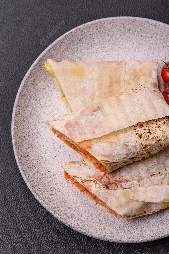 Delicioso rolo suculento ou shawarma com frango, tomate, salada e molho sobre um fundo escuro de concreto
