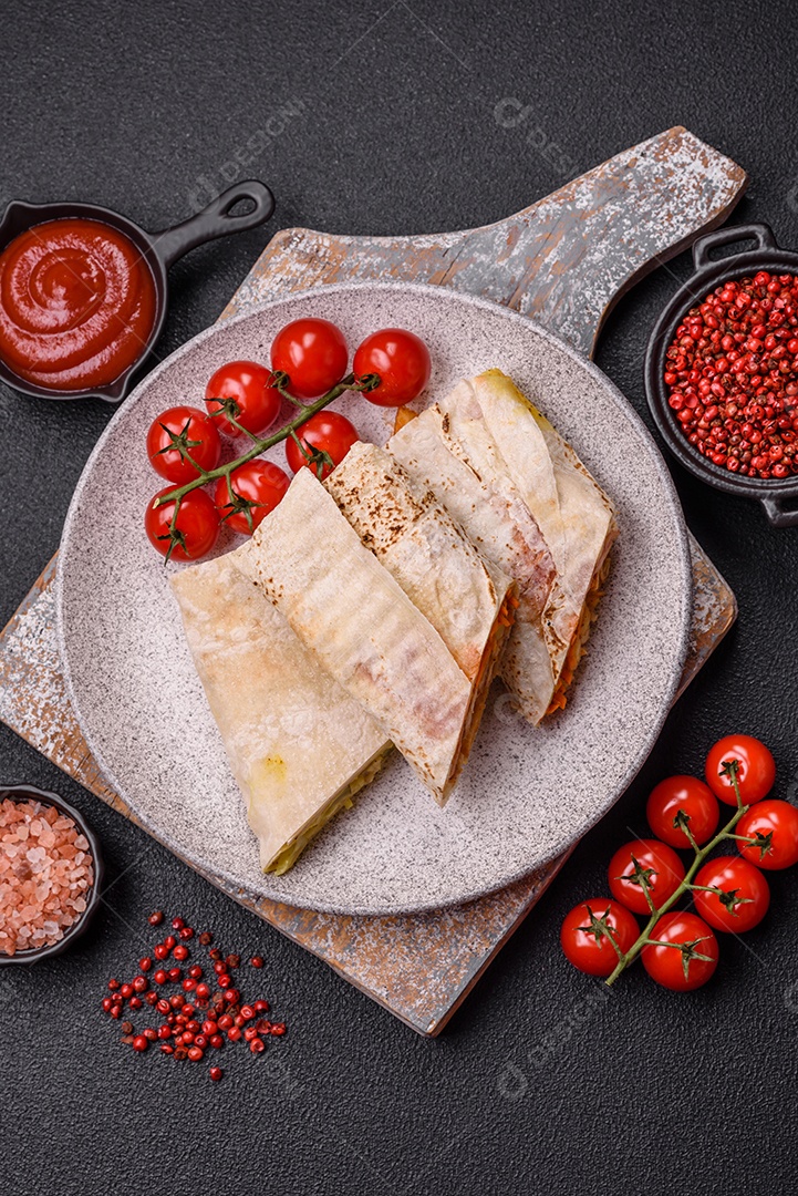 Delicioso rolo suculento ou shawarma com frango, tomate, salada e molho sobre um fundo escuro de concreto