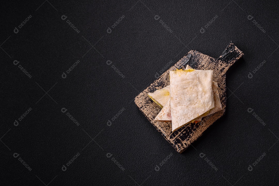 Delicioso rolo suculento ou shawarma com frango, tomate, salada e molho sobre um fundo escuro de concreto