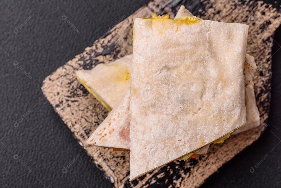 Delicioso rolo suculento ou shawarma com frango, tomate, salada e molho sobre um fundo escuro de concreto