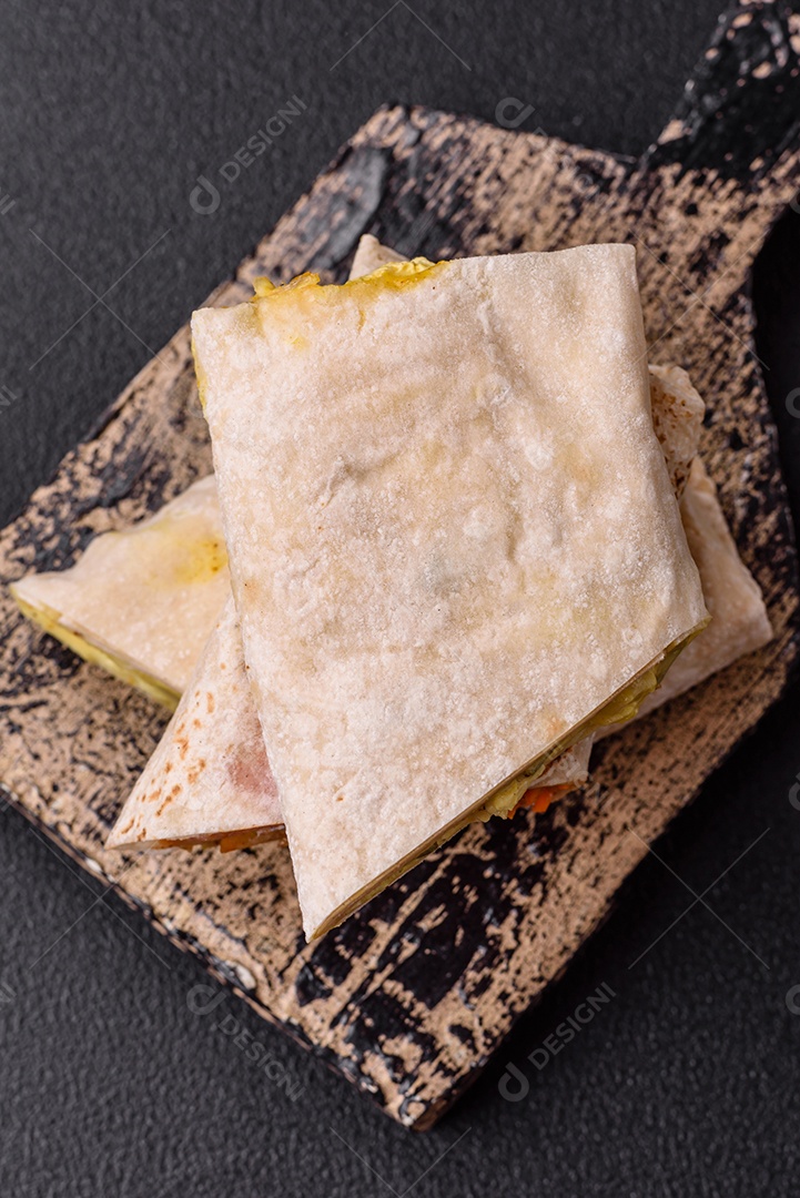 Delicioso rolo suculento ou shawarma com frango, tomate, salada e molho sobre um fundo escuro de concreto