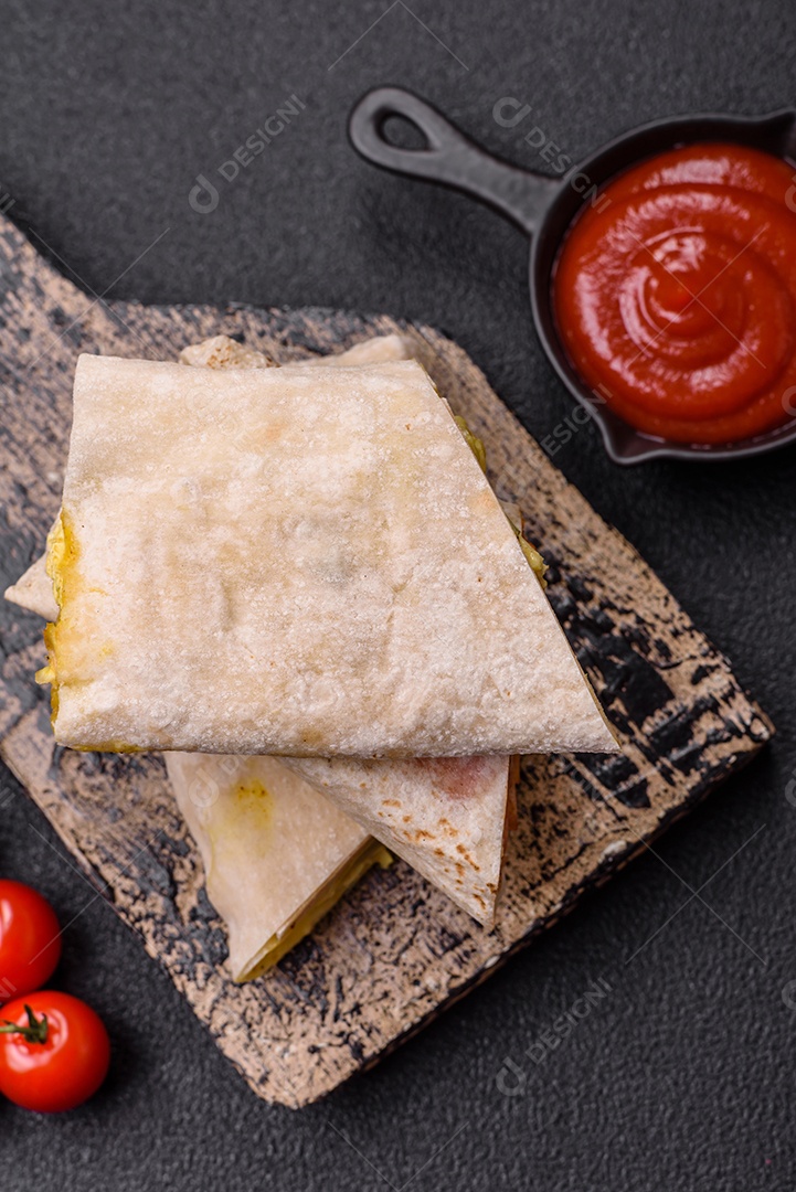 Delicioso rolo suculento ou shawarma com frango, tomate, salada e molho sobre um fundo escuro de concreto