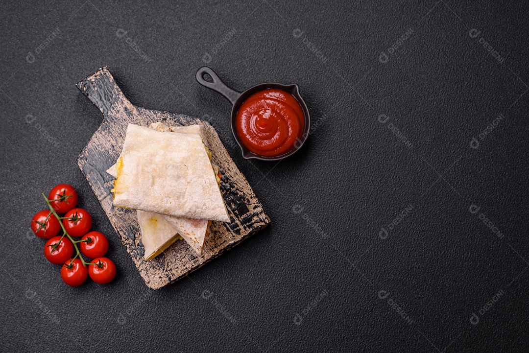 Delicioso rolo suculento ou shawarma com frango, tomate, salada e molho sobre um fundo escuro de concreto