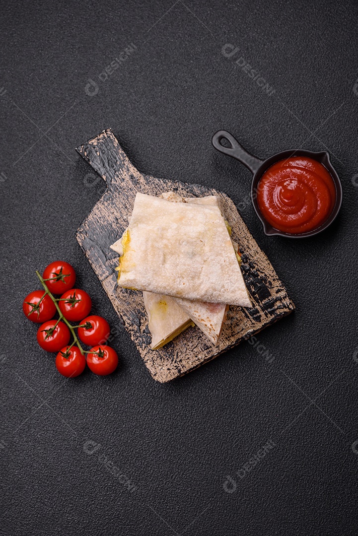 Delicioso rolo suculento ou shawarma com frango, tomate, salada e molho sobre um fundo escuro de concreto