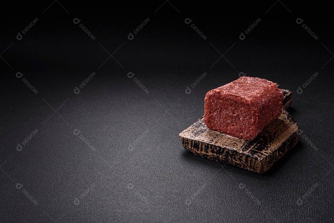 Delicioso presunto rosa enlatado com sal, especiarias e ervas sobre um fundo escuro de concreto