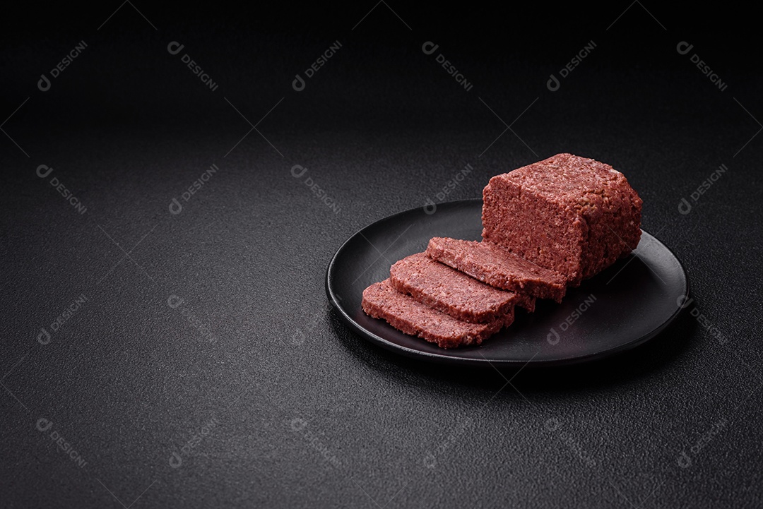 Delicioso presunto rosa enlatado com sal, especiarias e ervas sobre um fundo escuro de concreto