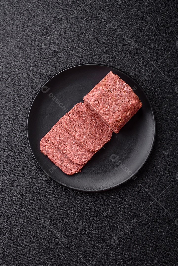 Delicioso presunto rosa enlatado com sal, especiarias e ervas sobre um fundo escuro de concreto