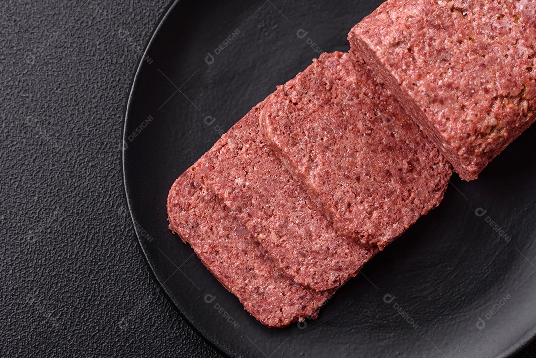 Delicioso presunto rosa enlatado com sal, especiarias e ervas sobre um fundo escuro de concreto