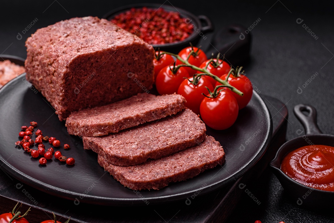 Delicioso presunto rosa enlatado com sal, especiarias e ervas sobre um fundo escuro de concreto