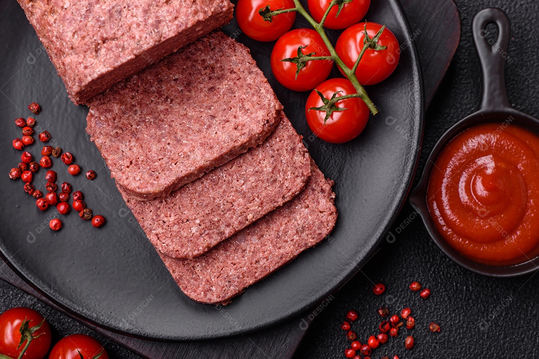 Delicioso presunto rosa enlatado com sal, especiarias e ervas sobre um fundo escuro de concreto