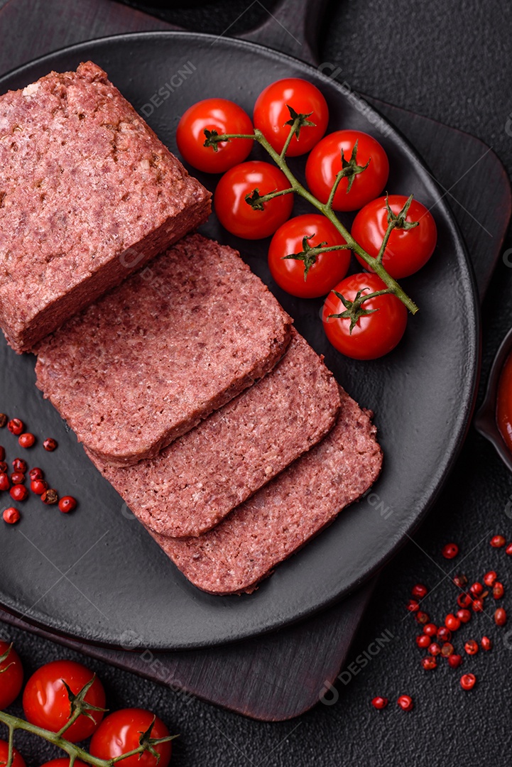 Delicioso presunto rosa enlatado com sal, especiarias e ervas sobre um fundo escuro de concreto