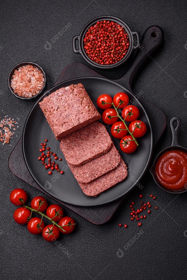 Delicioso presunto rosa enlatado com sal, especiarias e ervas sobre um fundo escuro de concreto