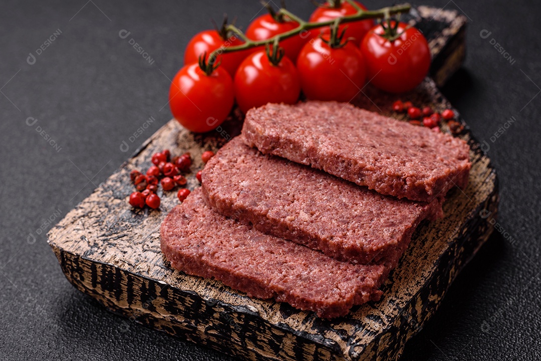 Delicioso presunto rosa enlatado com sal, especiarias e ervas sobre um fundo escuro de concreto