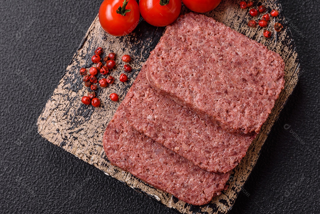 Delicioso presunto rosa enlatado com sal, especiarias e ervas sobre um fundo escuro de concreto