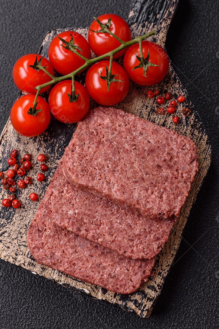 Delicioso presunto rosa enlatado com sal, especiarias e ervas sobre um fundo escuro de concreto