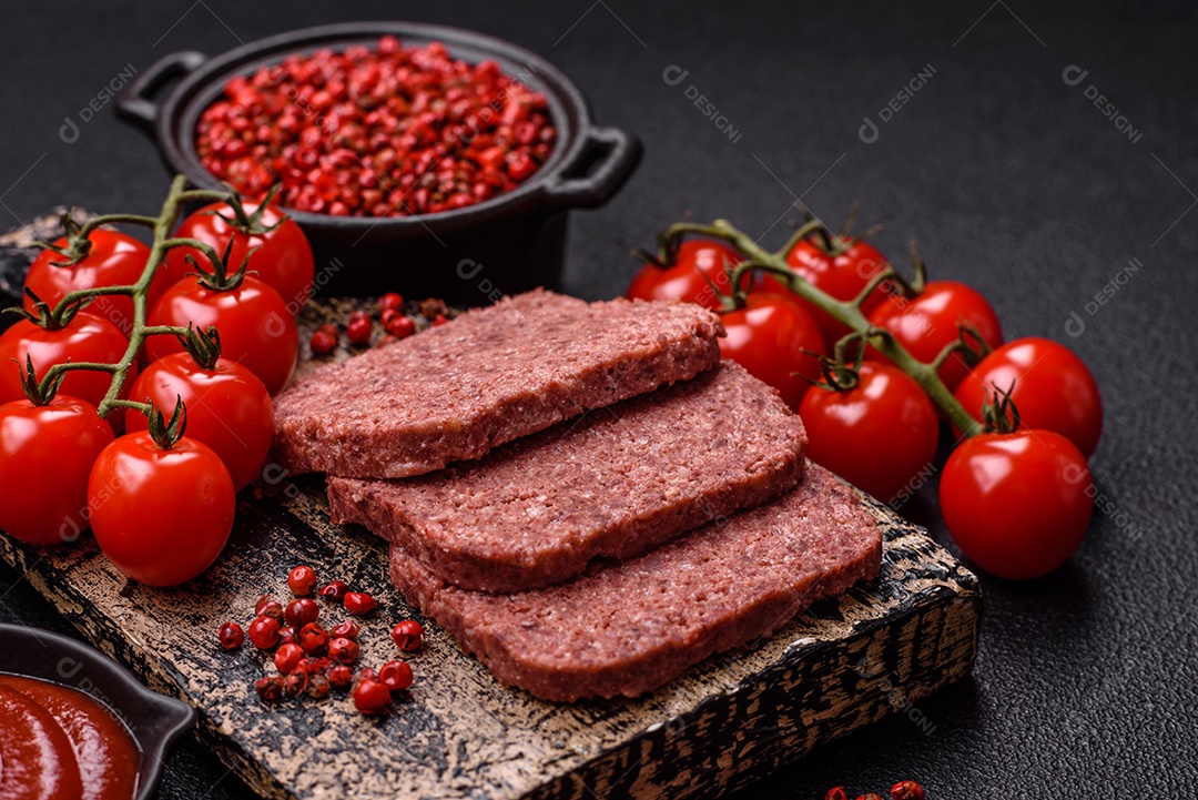 Delicioso presunto rosa enlatado com sal, especiarias e ervas sobre um fundo escuro de concreto