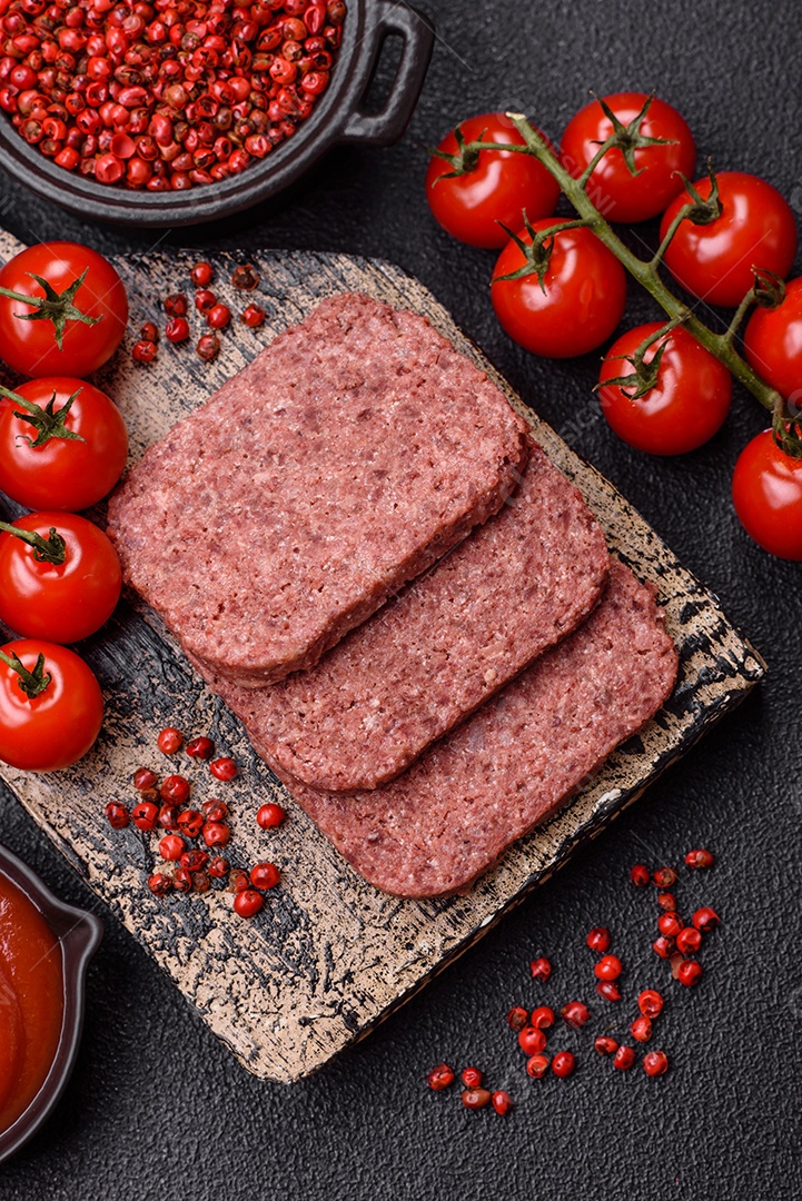 Delicioso presunto rosa enlatado com sal, especiarias e ervas sobre um fundo escuro de concreto