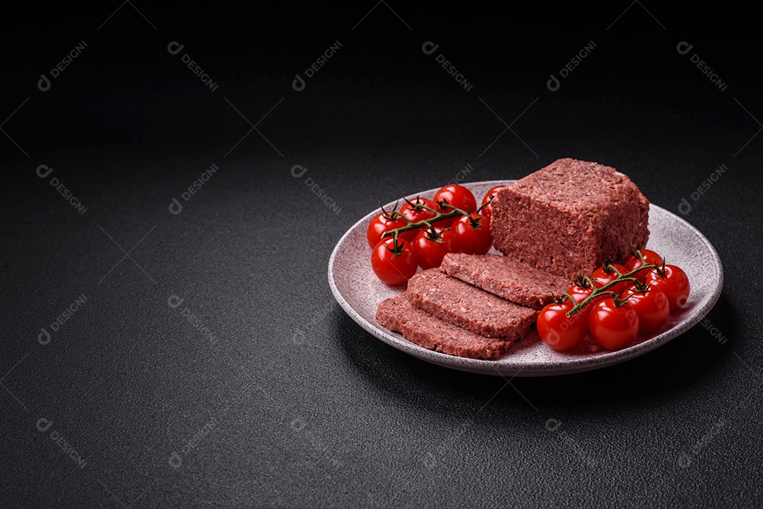 Delicioso presunto rosa enlatado com sal, especiarias e ervas sobre um fundo escuro de concreto