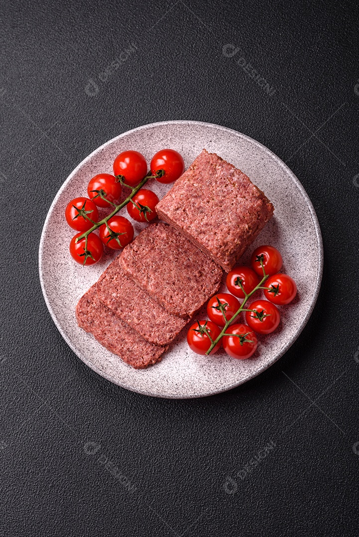 Delicioso presunto rosa enlatado com sal, especiarias e ervas sobre um fundo escuro de concreto