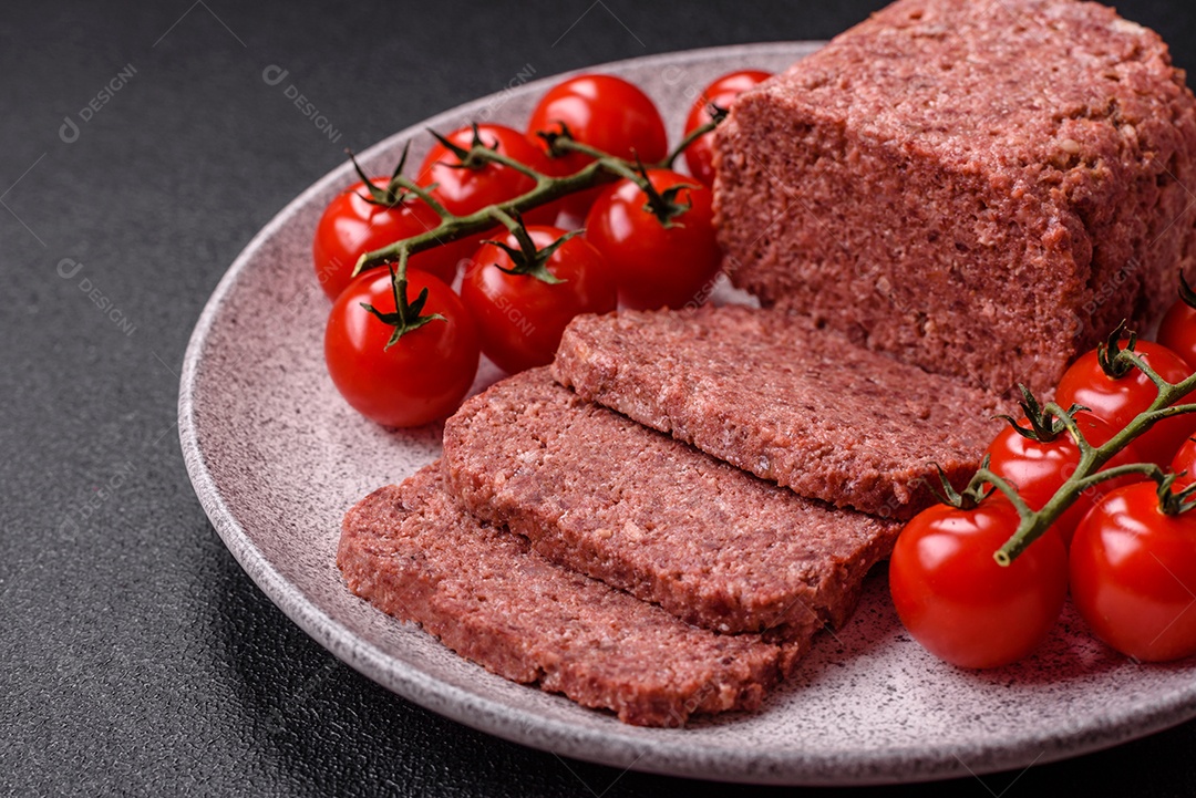 Delicioso presunto rosa enlatado com sal, especiarias e ervas sobre um fundo escuro de concreto