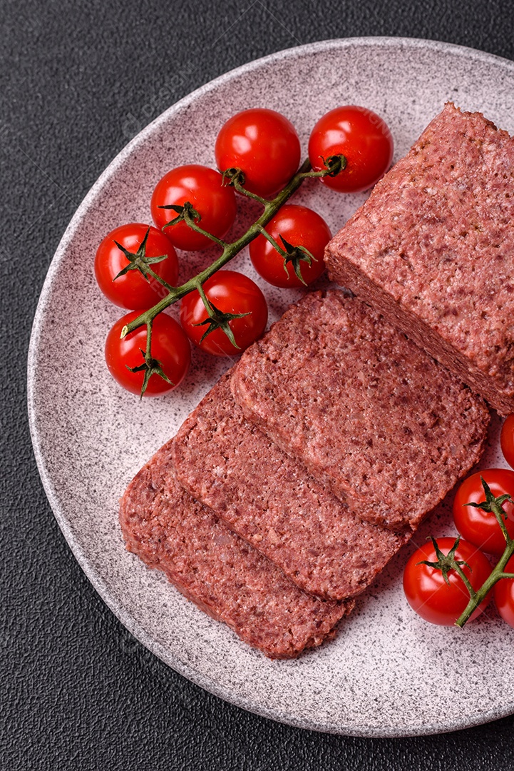 Delicioso presunto rosa enlatado com sal, especiarias e ervas sobre um fundo escuro de concreto