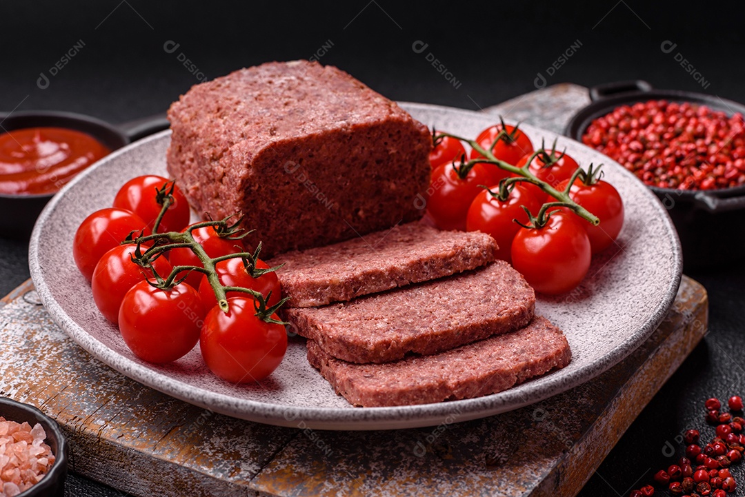 Delicioso presunto rosa enlatado com sal, especiarias e ervas sobre um fundo escuro de concreto