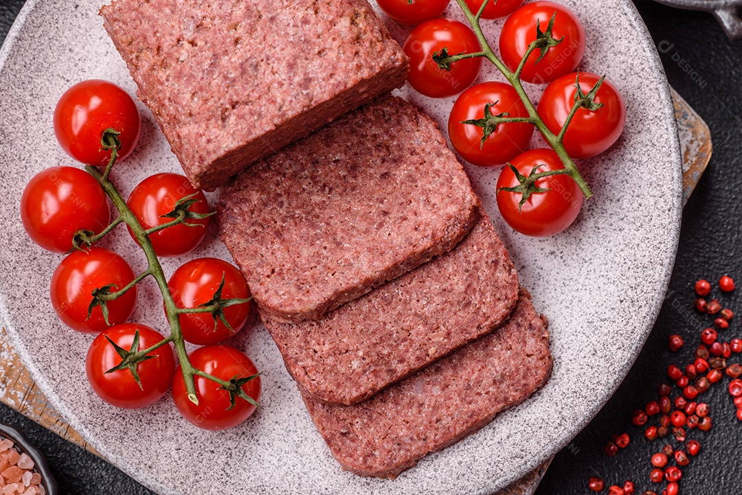 Delicioso presunto rosa enlatado com sal, especiarias e ervas sobre um fundo escuro de concreto