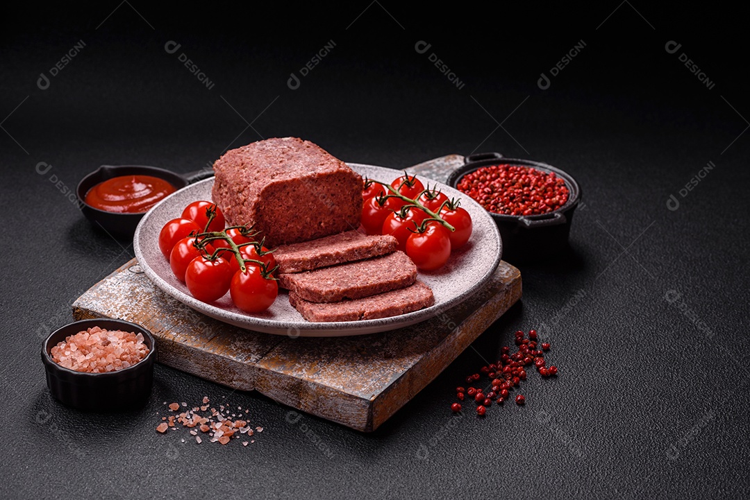 Delicioso presunto rosa enlatado com sal, especiarias e ervas sobre um fundo escuro de concreto