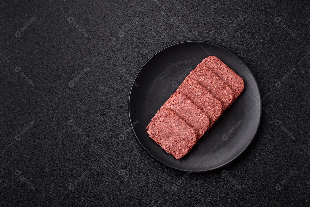 Delicioso presunto rosa enlatado com sal, especiarias e ervas sobre um fundo escuro de concreto