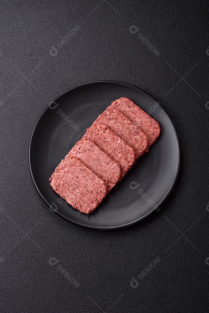 Delicioso presunto rosa enlatado com sal, especiarias e ervas sobre um fundo escuro de concreto