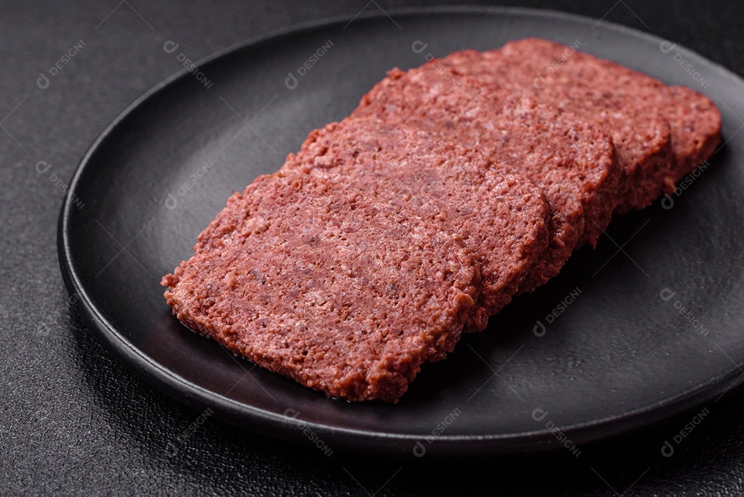 Delicioso presunto rosa enlatado com sal, especiarias e ervas sobre um fundo escuro de concreto