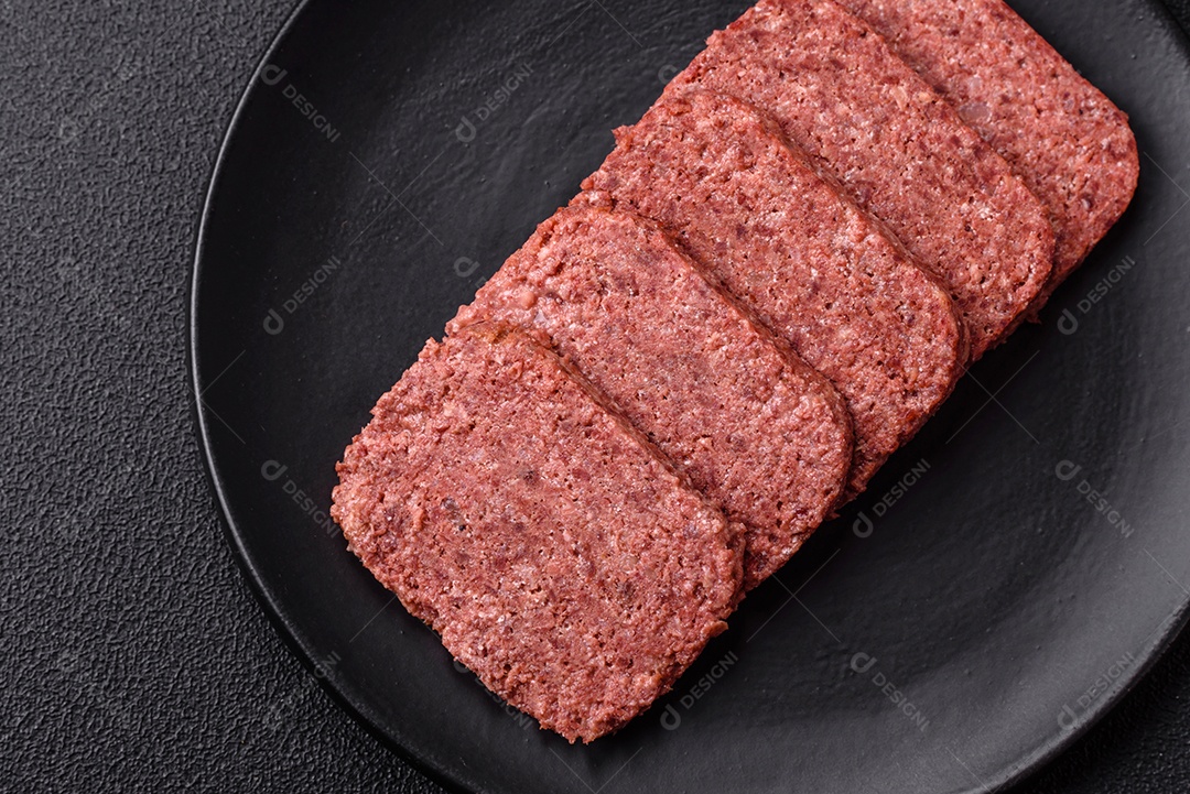 Delicioso presunto rosa enlatado com sal, especiarias e ervas sobre um fundo escuro de concreto