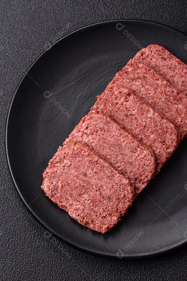 Delicioso presunto rosa enlatado com sal, especiarias e ervas sobre um fundo escuro de concreto