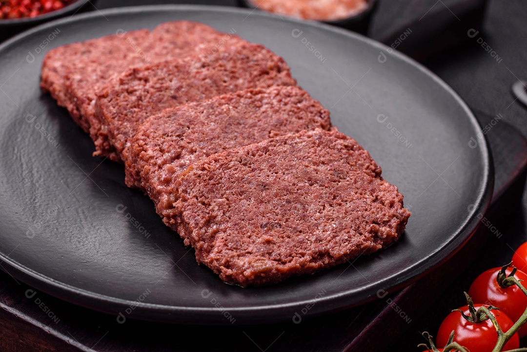 Delicioso presunto rosa enlatado com sal, especiarias e ervas sobre um fundo escuro de concreto