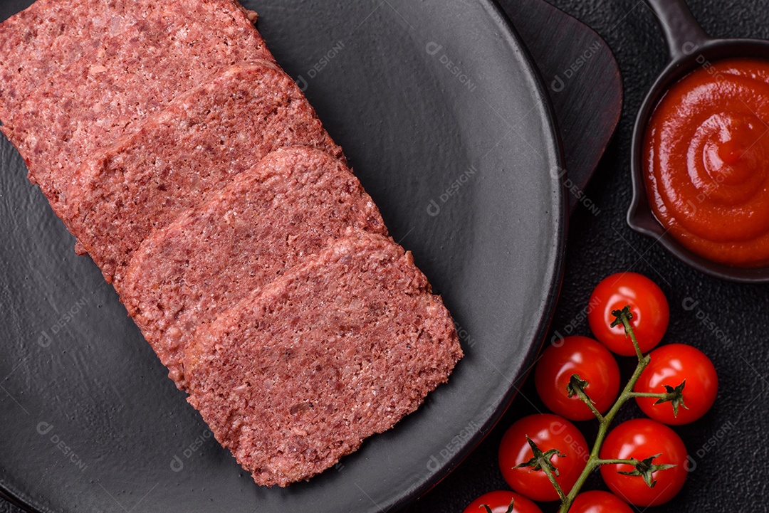 Delicioso presunto rosa enlatado com sal, especiarias e ervas sobre um fundo escuro de concreto